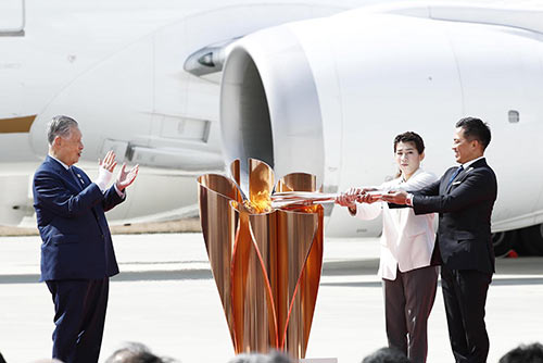 東京2020オリンピック聖火リレー聖火到着式で点火する野村忠宏さんと吉田沙保里さん。左は森喜朗組織委員会会長（当時）